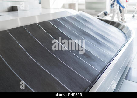 Tour de l'aéroport en caoutchouc noir carrousel des bagages (convoyeur à bande) avec un châssis en acier brillant à la lumière du jour le matin, avec peu de peop Banque D'Images