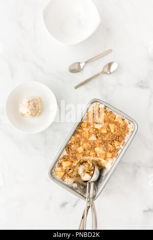 Crumble aux pommes fait maison avec de la crème glacée vanille, sauce caramel, pommes et cannelle charlottes en récipient en métal avec cuillère à crème glacée et à la pétanque. Banque D'Images