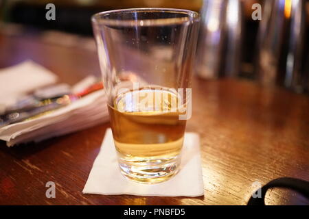 Une bière à moitié vide se trouve sur un bar Banque D'Images