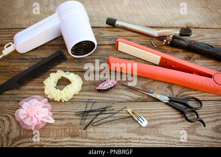 Accessoires cheveux : sèche-cheveux, fer à friser les cheveux, fer à repasser, peigne, ciseaux, pinces à cheveux sur le vieux fond de bois. Image tonique Banque D'Images