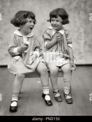 Années 20, DEUX PETITES FILLES SITTING ON BENCH EATING ICE CREAM CONES ET PARLER - f2181 HAR001 COMMUNICATION HARS RIRE HEUREUX JOIE DOUBLE LITS JUMEAUX IDENTIQUES FEMMES PORTRAIT DE SANTÉ DE LA VIE DE L'AMITIÉ ESPACE COPIE MATCH DEMI-LONGUEUR EXPRESSIONS SŒURS SŒURS B&W BRUNETTE MATCHING STYLES Gaies même bonheur et sourires d'ENFANT DE CÔNES DE MARY JANE MARY JANES CONNEXION joyeuse à l'apparence élégante de la MODE EN DOUBLE Les juvéniles se ressemblent l'unité NOIR ET BLANC DE L'ORIGINE ETHNIQUE CAUCASIENNE HAR CLONE001 old fashioned PLAYMATES Banque D'Images