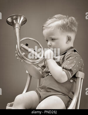 1940 YOUNG BOY SITTING IN CHAIR SOUFFLE MUSICAL EN LAITON CORNE - j6190 HAR001 NOIR ET BLANC de la station de recherche de l'origine ethnique caucasienne COR HAR001 old fashioned Banque D'Images