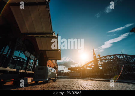 Belle retro style location de paniers sur la place pavée. Arch bridge plus de canaux avec Sankt Katherinen église dans l'arrière-plan. Quartier d'entrepôts à Hambourg, Allemagne. Coucher du soleil chaud de la lumière. De style Renaissance Banque D'Images