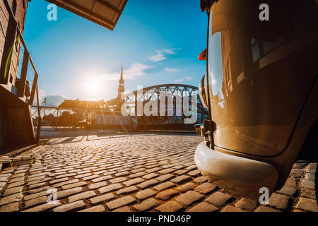 Libre de style rétro voiture sur la place pavée. Arch bridge plus de canaux avec Sankt Katherine église dans l'arrière-plan. De Speicherstadt Hamburg. Coucher du soleil chaud et ciel bleu Banque D'Images