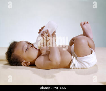 1960 AFRICAN AMERICAN BABY LYING ON DE L'ALCOOL À PARTIR DE LA BOUTEILLE - kn738 HAR001 HARS JUVÉNILES SOIF HAR001 old fashioned américains africains Banque D'Images