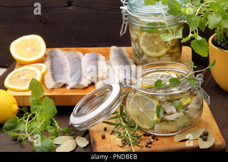 Filet de hareng mariné frais et sain avec le citron, le poivre, les herbes et l'oignon sur fond de bois Banque D'Images