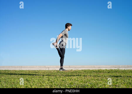 L'homme s'étend la jambe avant l'exécution d'un espace réservé au texte Banque D'Images