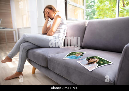 Lonely Woman Sitting on Sofa avec photographie déchirée Banque D'Images