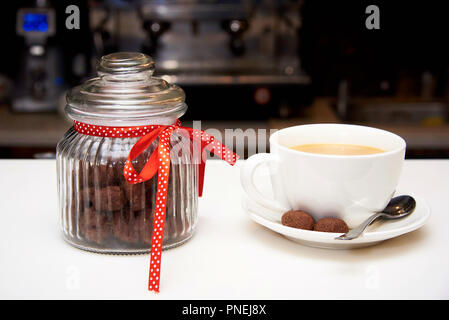 Bocal en verre avec des biscuits et une tasse de café sur la barre. Banque D'Images