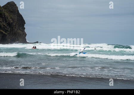 Piha beach, Auckland, Nouvelle-Zélande - le 17 décembre 2016 : kayak et surf la mer de Tasman rugueuse à Piha beach à Auckland, en Nouvelle-Zélande. Banque D'Images