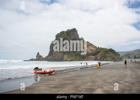 Piha beach, Auckland, Nouvelle-Zélande - Décembre 17,2016 : les touristes et les sauveteurs par la mer de Tasmanie surf à Piha beach à Auckland, en Nouvelle-Zélande. Banque D'Images