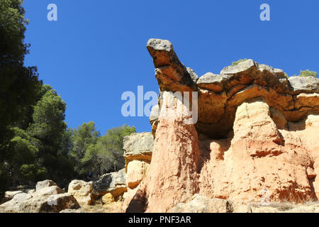 Une roche rouge en saillie avec des arbres et un ciel bleu profond dans le style canyon hills de Anento, petite ville de l'Aragon, Espagne Banque D'Images