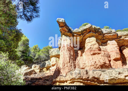 Une roche rouge en saillie avec des arbres et un ciel bleu profond dans le style canyon hills de Anento, petite ville de l'Aragon, Espagne Banque D'Images