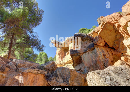 Une roche rouge en saillie avec des arbres et un ciel bleu profond dans le style canyon hills de Anento, petite ville de l'Aragon, Espagne Banque D'Images