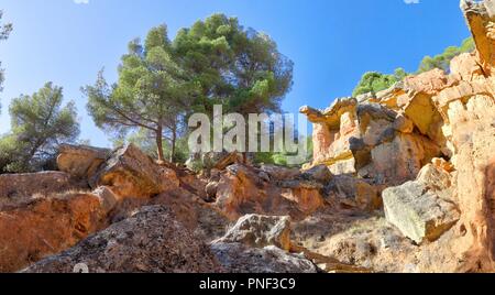 Une roche rouge en saillie avec des arbres et un ciel bleu profond dans le style canyon hills de Anento, petite ville de l'Aragon, Espagne Banque D'Images