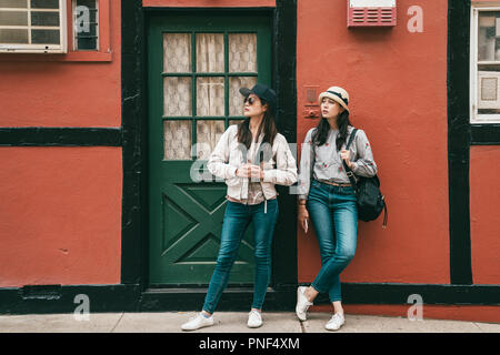 Les jeunes amis proches et d'attendre debout en face d'un bâtiment tout en tourisme dans une ville magnifique. Banque D'Images