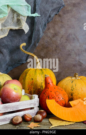 Tas de citrouilles récoltés orange, des feuilles sèches, les pommes, les châtaignes sur une table en bois, aux couleurs rétro. Jour de Thanksgiving concept. Background vintage rustique. Au Banque D'Images