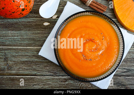 Délicate purée de potiron dans un bol en verre noir sur une table en bois. Vue d'en haut. Banque D'Images