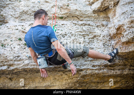 Photo de l'arrière de l'escalade sports man on rock Banque D'Images