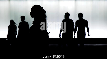 Silhouettes floues de jeunes marchant dans le motion blur en face de l'immeuble moderne dans la nuit Banque D'Images