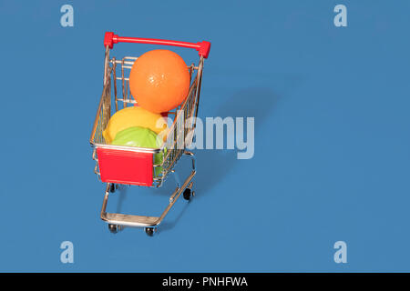 Toy panier chariot rempli de fruits et légumes en plastique sur un fond bleu avec l'espace pour copier et texte Banque D'Images