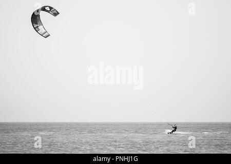 Kiteboarder tirant d'air et d'obtenir des astuces sur un jour d'été parfait avec ciel bleu clair. Strret bardeaux, Suffolk, UK Banque D'Images