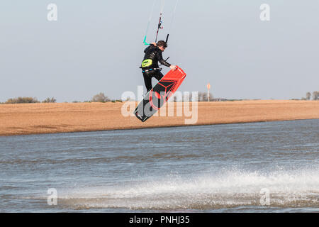Kiteboarder tirant d'air et d'obtenir des astuces sur un jour d'été parfait avec ciel bleu clair. Strret bardeaux, Suffolk, UK Banque D'Images