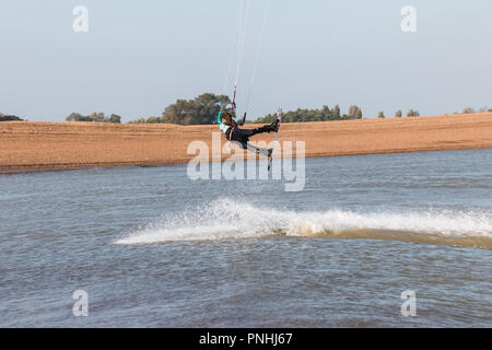 Kiteboarder tirant d'air et d'obtenir des astuces sur un jour d'été parfait avec ciel bleu clair. Strret bardeaux, Suffolk, UK Banque D'Images