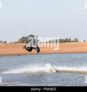 Kiteboarder tirant d'air et d'obtenir des astuces sur un jour d'été parfait avec ciel bleu clair. Strret bardeaux, Suffolk, UK Banque D'Images