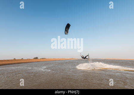 Kiteboarder tirant d'air et d'obtenir des astuces sur un jour d'été parfait avec ciel bleu clair. Strret bardeaux, Suffolk, UK Banque D'Images
