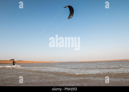 Kiteboarder tirant d'air et d'obtenir des astuces sur un jour d'été parfait avec ciel bleu clair. Strret bardeaux, Suffolk, UK Banque D'Images