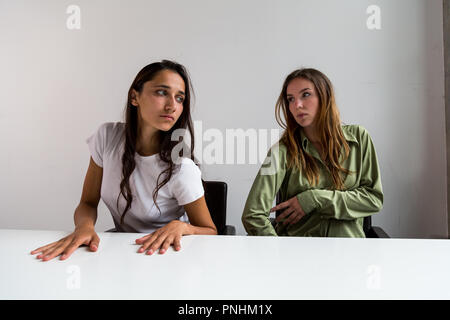 Deux femmes effectuant des poses artistiques assis à grand bureau. Plan moyen. Sur face avant. Banque D'Images