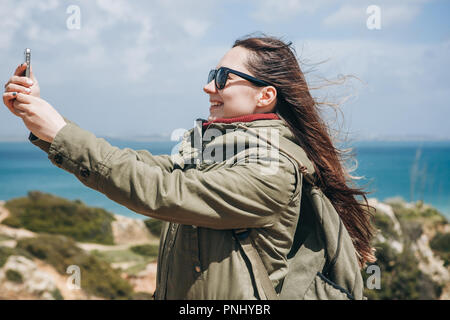 Une fille prend touristique une belle vue ou est-ce qu'un ou communique avec quelqu'selfies en ligne en utilisant un téléphone cellulaire. Banque D'Images