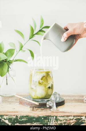 Matcha latte glacé avec du lait couler en verre pichet fron Banque D'Images