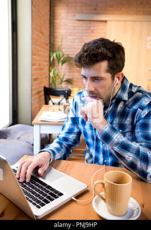 Jeune homme avec portable et café ou thé surpris Banque D'Images