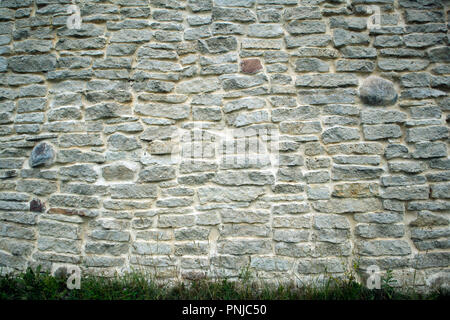 Maçonnerie antique, fragment de l'ancienne muraille de brique calcaire en ruine et de l'herbe dans le fond Banque D'Images