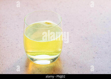 Comprimé jaune de vitamine C se dissout dans de l'eau Banque D'Images