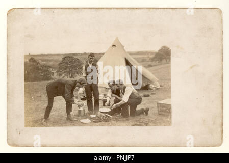 Carte postale édouardienne de jeunes hommes camping à la campagne, la cuisine ouverte sur une fireout tente de toile à l'extérieur, vers 1904, Royaume-Uni Banque D'Images