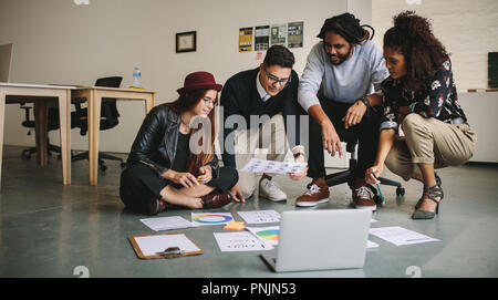 Des collègues de travail discutent sitting on floor with laptop et documents d'affaires. Les gens d'affaires créatifs discuter des idées de répandre leur wor Banque D'Images