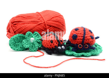 Coccinelle crochet blanc sur fond rouge isolé. laine ball. green clover Banque D'Images