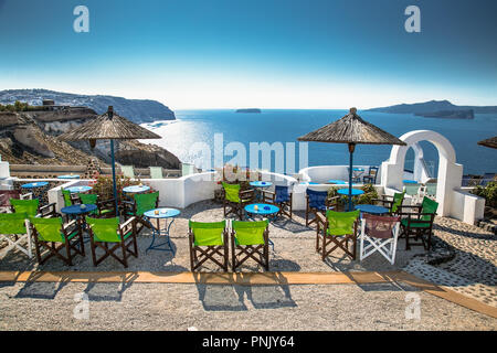 Des tables et des chaises sur le toit avec une vue romantique panorama sur l'île de Santorin, Grèce, sur la mer Egée. Banque D'Images