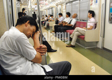 Les Japonais dormir et équitation le train tôt le matin à Tokyo, Japon Banque D'Images