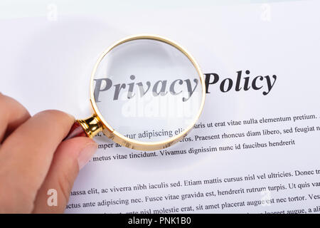 Close-up of a Woman's Hand Holding Loupe sur Formulaire de Politique de confidentialité Banque D'Images