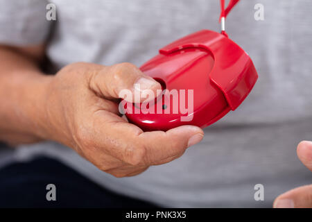 Close-up of a Senior Man's Hand Holding Red alarme personnelle Banque D'Images