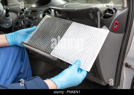 Le remplacement d'une vieille voiture filtre à air cabine. Mécanicien auto de protection dans des gants de travail, tenue sale et nettoyer le filtre à air Banque D'Images