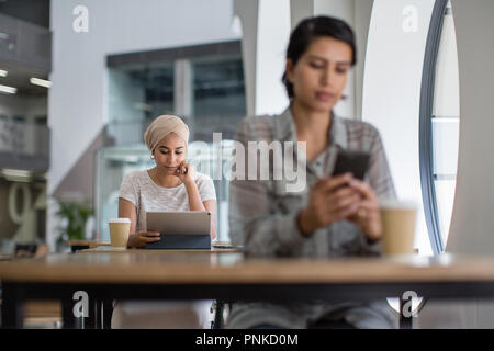 Femme musulmane à l'aide d'une tablette numérique dans un café Banque D'Images