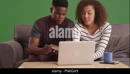 Happy Black couple millénaire magasinage en ligne avec carte de crédit sur un écran vert Banque D'Images