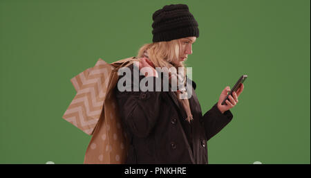 Femme blonde avec des sacs de shopping phone sur écran vert Banque D'Images