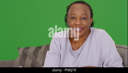 Une vieille femme noire heureusement regarde la caméra sur un écran vert Banque D'Images