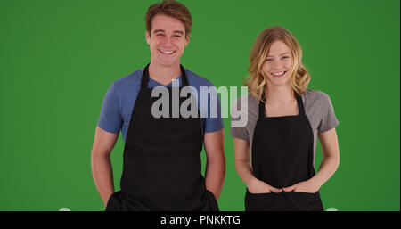 Male et femelle restaurant employés posant dans des tabliers sur écran vert Banque D'Images